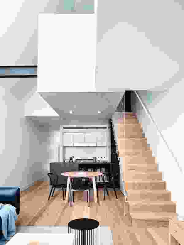 From the ground floor, the second level appears as a sequence of volumes balanced over the kitchen and stair.