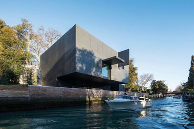 The brooding black box cantilevers over the canal, its recessed ground floor housing service areas and an office.