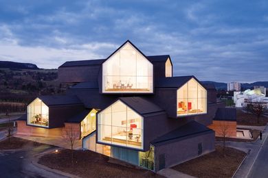 Elevated above the Vitra Campus in Germany, the building form is made up of a series of stacked, long, gabled roof telescopes.