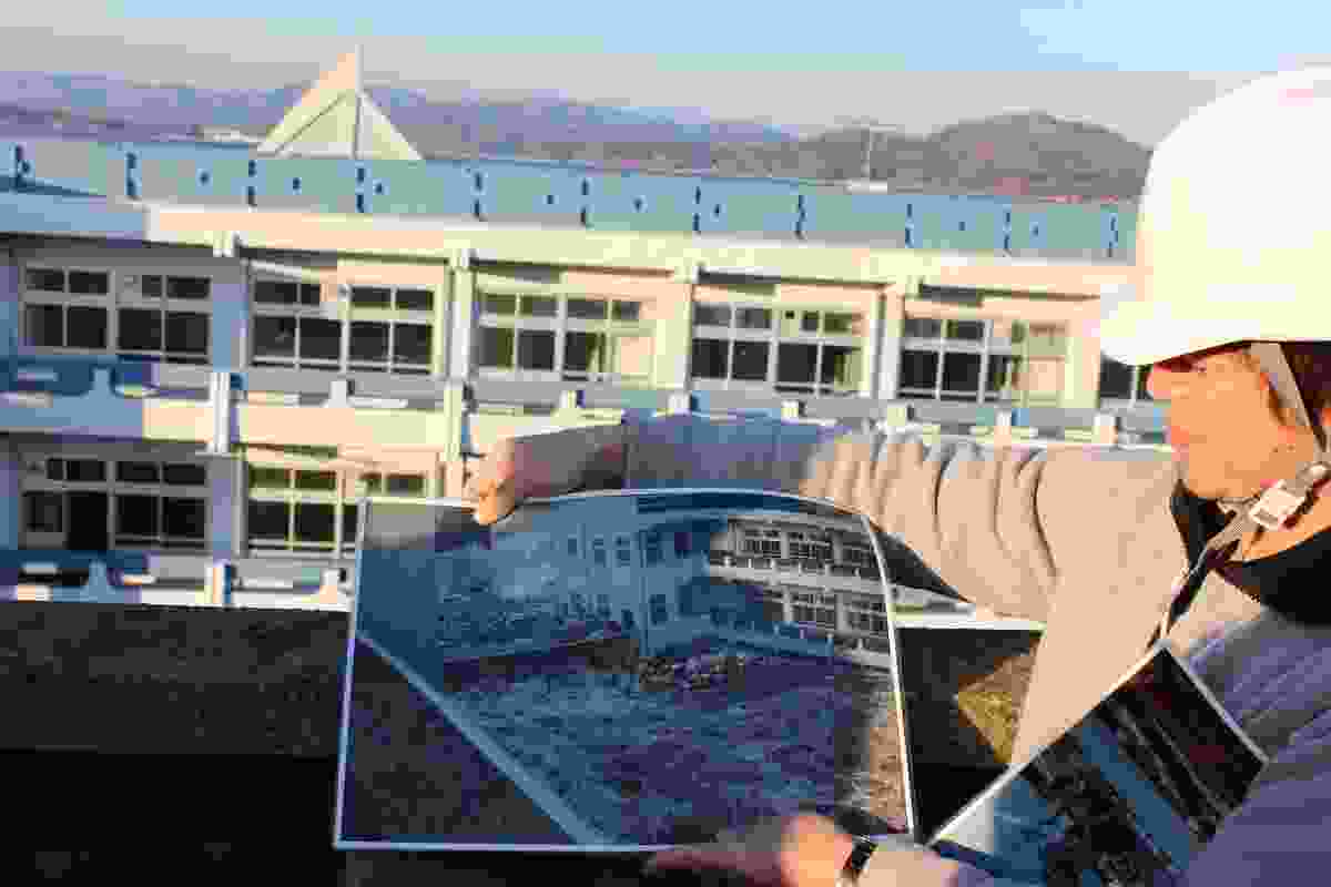 Our guide holds a photo of surging water taken from the high school roof on the day of the 2011 tsunami. 