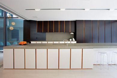 A large island bench topped with polished concrete runs the length of the kitchen.