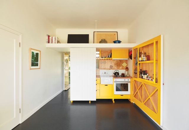 The splash of colour in the kitchen cabinetry was inspired by the bold yellow floor of Le Corbusier’s Cabanon. Artwork (L-R): Sally Ross; Minnie Pwerle.