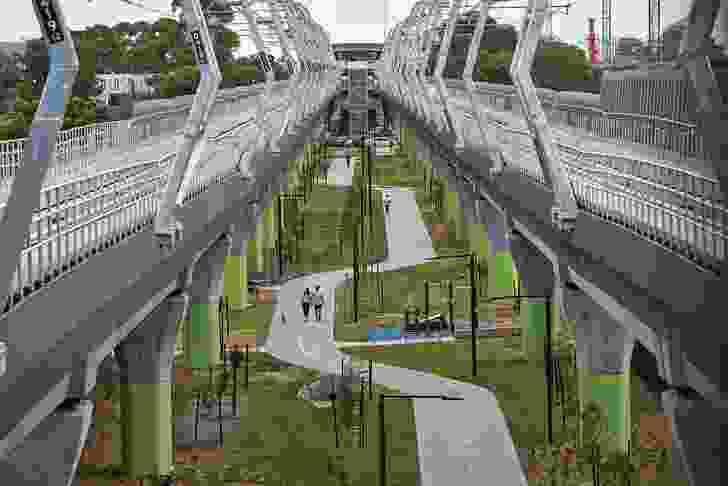 Parklands framed by new tree plantings unfold beneath the rail line's concrete viaducts, providing additional green space for the surrounding communities.