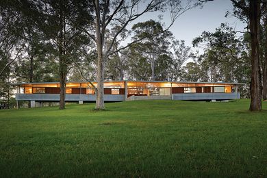 The house consists of a central communal space touching the ground, with a cantilevered sleeping wing floating on either side.