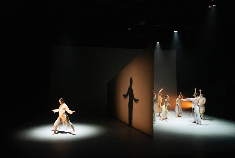 At the start of the performance, a monolithic, wedge-shaped wall slices the stage in two.