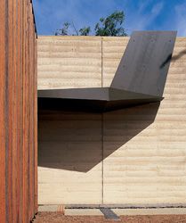 Folded
metal, clipped onto the rammed-earth wall, defines the
entry.