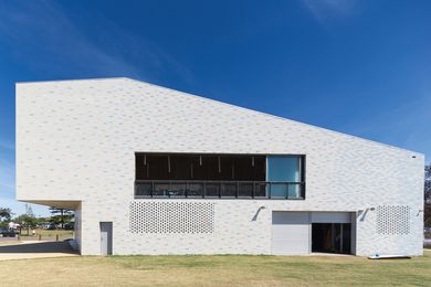 The striking and monolithic form of the north elevation is punctured only by a long balcony, garage doors and breezeblock screens on the lower level.