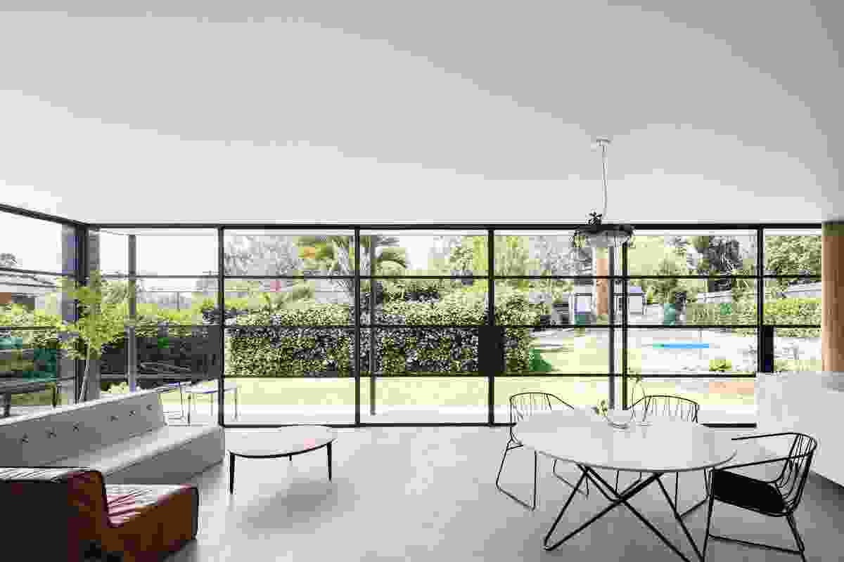 The kitchen, dining and living room look out to the garden through glass walls and sliding doors framed in fine steel.