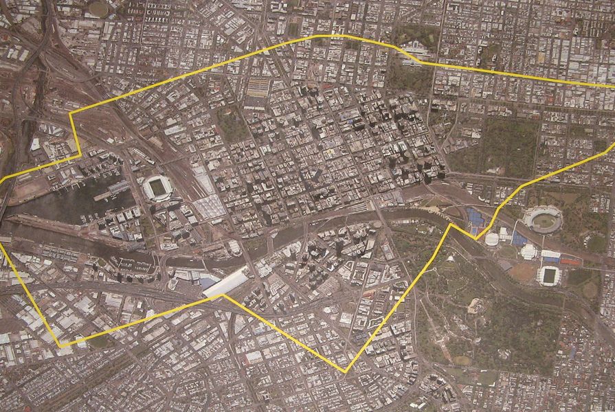 The Hazelwood Open Cut Mine boundary plotted in yellow over an aerial image of central Melbourne at the same scale. 