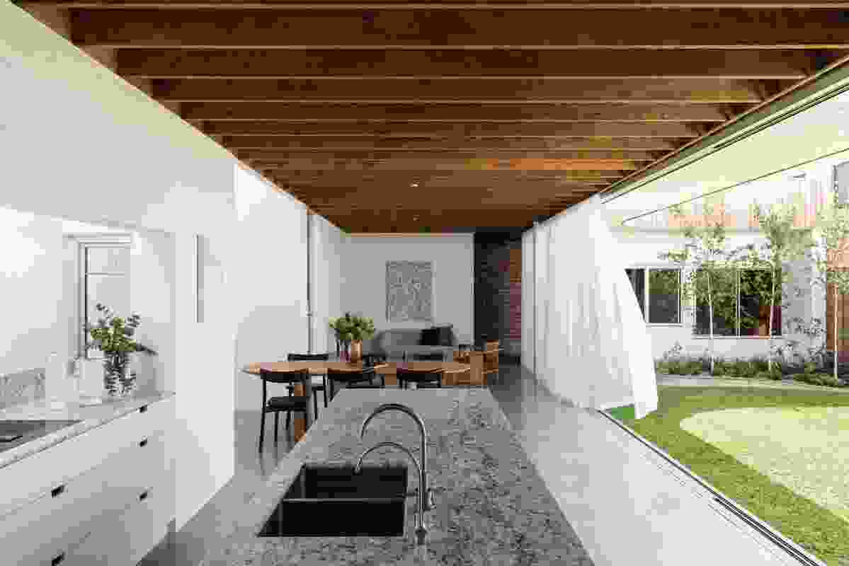 Courtyard, kitchen, dining and lounge flow together so the home feels expansive despite its narrow site. Artwork: Lloyd Kwilla.