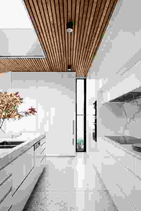 The width of the corridor leading to the kitchen frames the island bench and the skylight above.