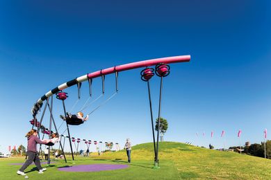 A semicircular swing set parallels the nearby grass mound.