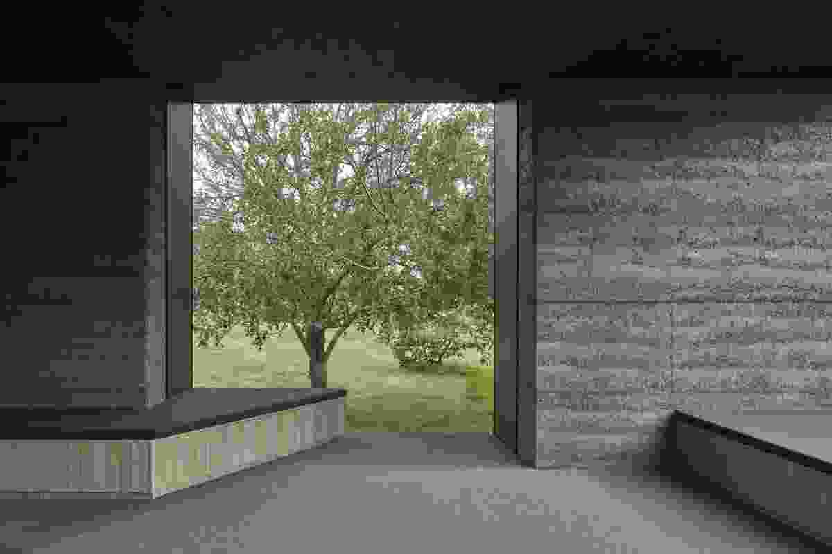 A window on the southern side of the home incorporates built-in seating facing the trees.