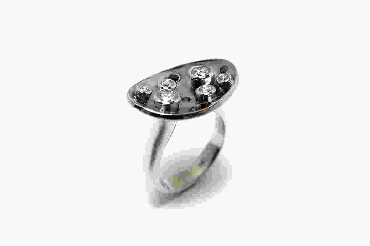 Genevieve Lilley ring: 18 carat white gold around a black rhodium-lined dish set with 6 bezel-set white diamonds and 5 hammerset black diamonds.