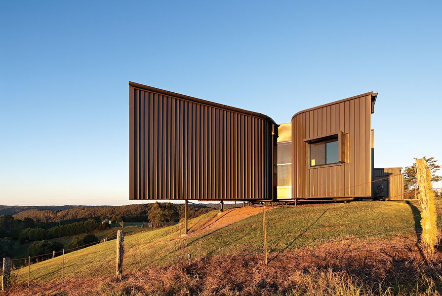 The earthy coloured, textured cladding blends into the hillside.