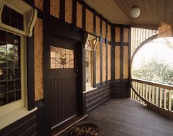N°4 Entrance verandah, with views to the east framed by the swagged ogee arch and slatted balustrade. The hopper and sash windows are seen by the door.