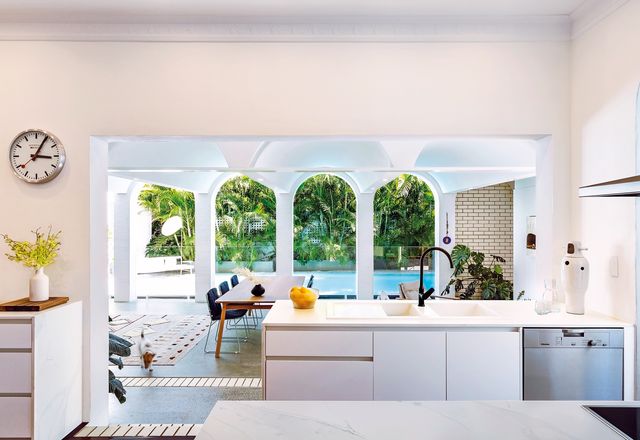 A large opening cut into the wall opens up the kitchen to the pool, garden and sky.