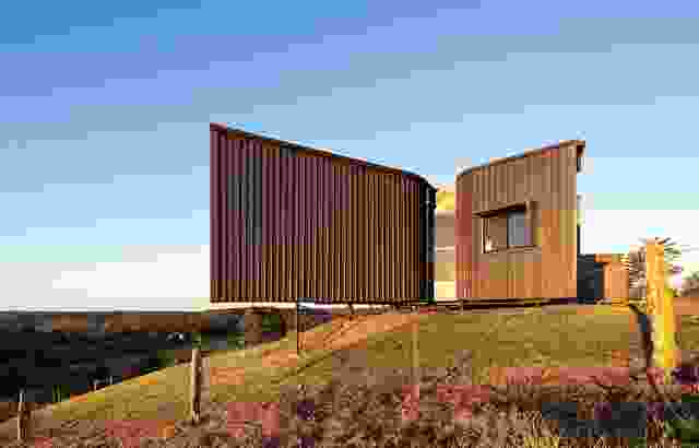 The earthy coloured, textured cladding blends into the hillside.