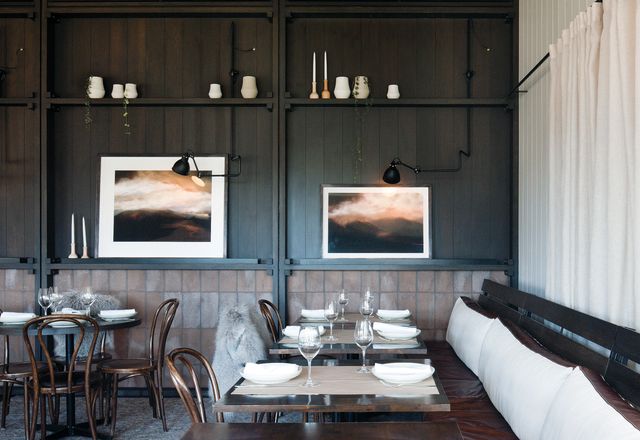 The dining room’s panelled wall displays artwork and vases, while the lower section is finished in warm brick tiles. Artwork: Rebekah Stuart.