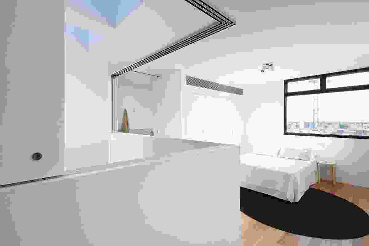 The bedroom on the third floor borrows light from the adjacent void.