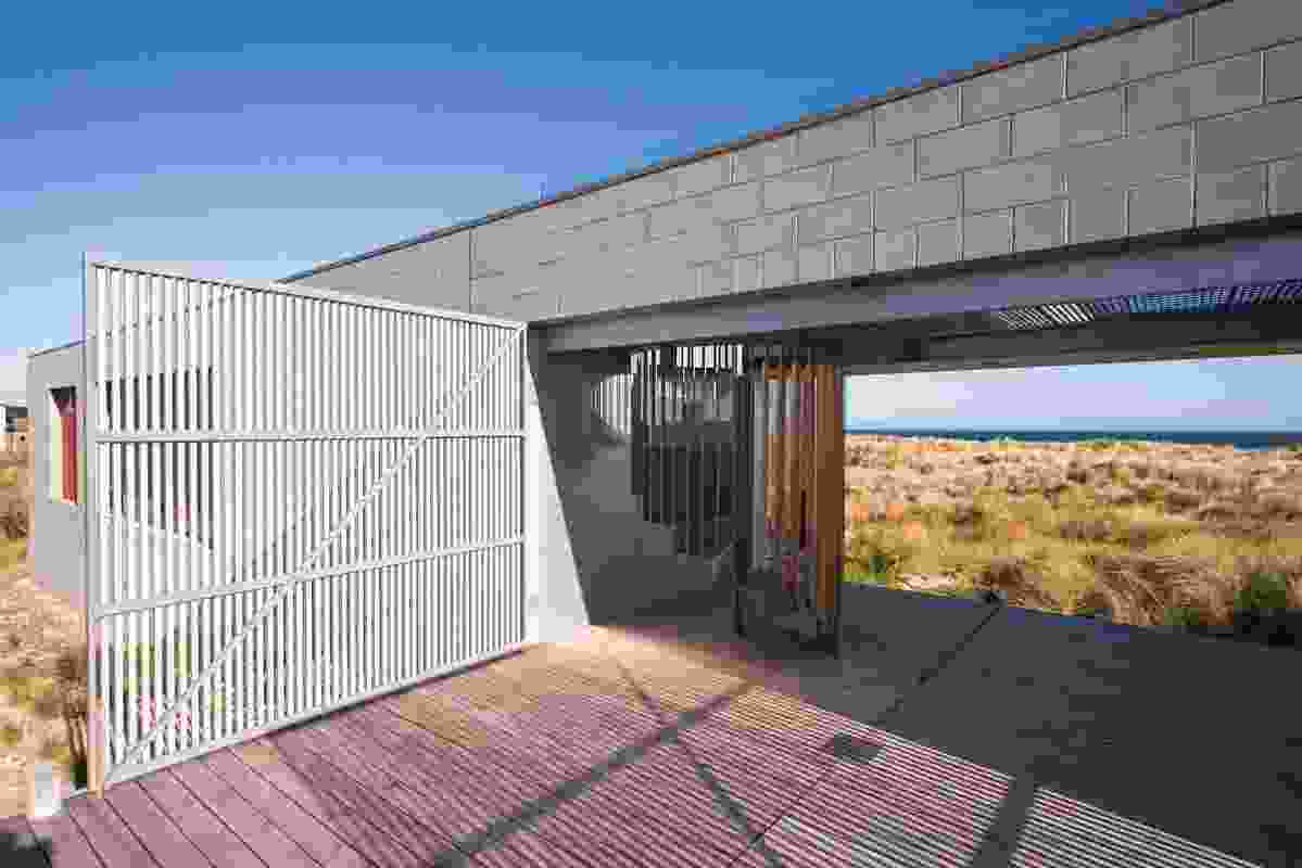 A timber entry deck at the Churchill House splits two pavilions and opens to a view of dunes and ocean.
