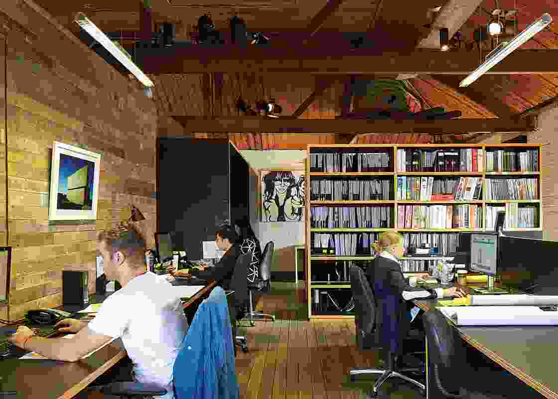 The Wolveridge Architects’ team in their office in Collingwood, Melbourne. Photograph of Torquay House (on left wall) by Derek Swalwell. Artwork: Guz, Love me or Else, 2006.