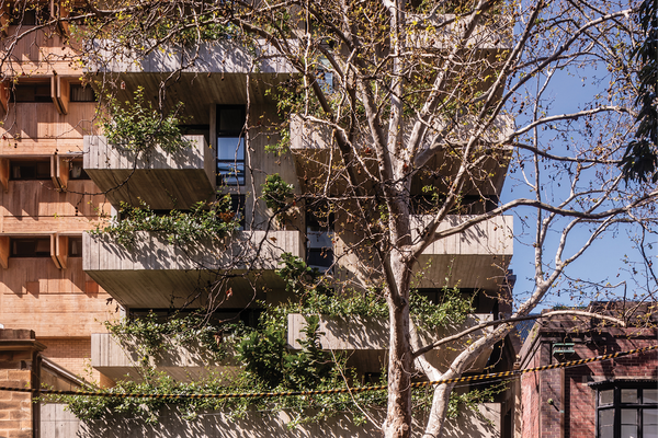 Located in the inner-Sydney suburb of Surry Hills, Woods Bagot’s residential and retail building presents a memorable facade of staggered concrete forms and dense foliage.