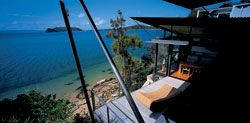 Looking down at the deck from
above the living room, with cliff, scrub and beach below
and harbour beyond.Photograph Anthony Browell