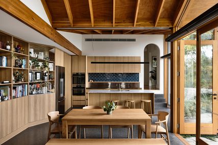 Built-in timber bookshelves that edge the living and dining room are accented by exposed chalk-toned brick.