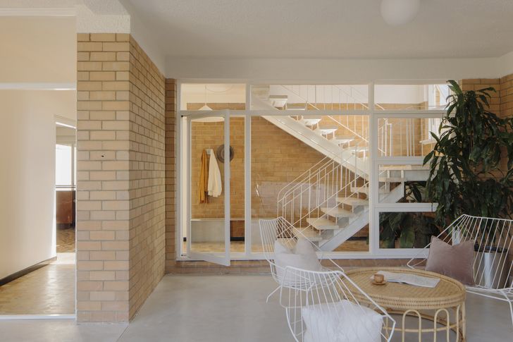 The staircase's terrazzo treads and slender railings create a captivating play of light and shadow against the walls.