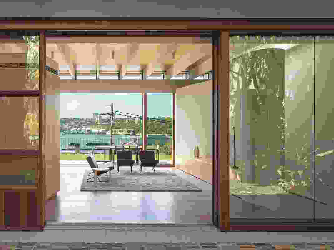 View from the front garden, through the living space to the harbour. The simply finished space is bathed in warm light.