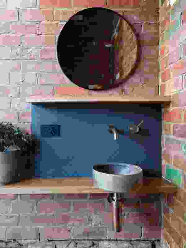 In the powder room, minimal additions mean the red brick walls and sandstone footings of the old house are left to be celebrated.