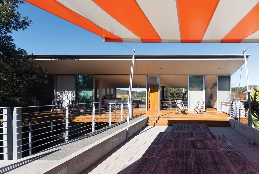 The northern deck features a sunken lounge with a large retractable awning in a wide bright stripe, recalling beach umbrella patterns.