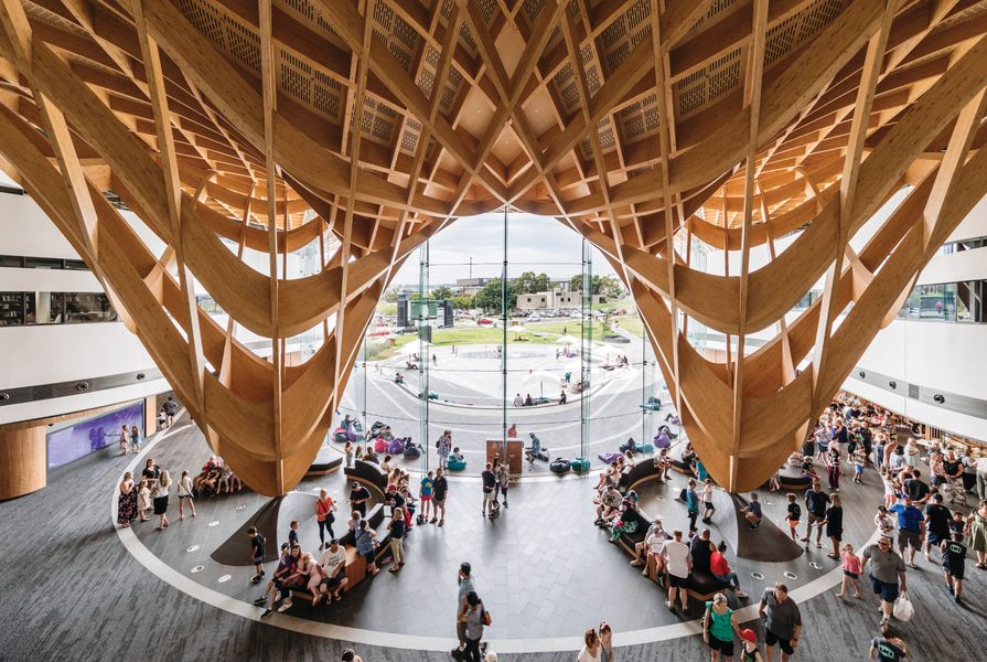 Beneath the roof, the woven timber structure is pulled dramatically down at two points to create a monumental and generous civic entry.
