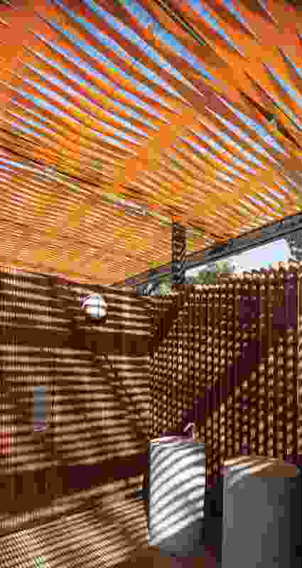 The pavilions are roofed with woven strips of orange webbing, which cast vibrating shadows.