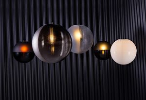 The blown-glass spheres of the Stellar pendant lighting collection for Pulpo are divided into hemispheres of textured and smooth.