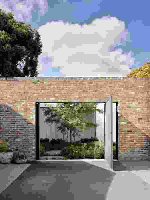 A large pivot door connects one courtyard to a long existing driveway, now a shared neighbourhood space.