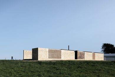 A long, heavy masonry wall protects the house from the road and a custom mortar technique adds shadow and depth to the external surfaces.