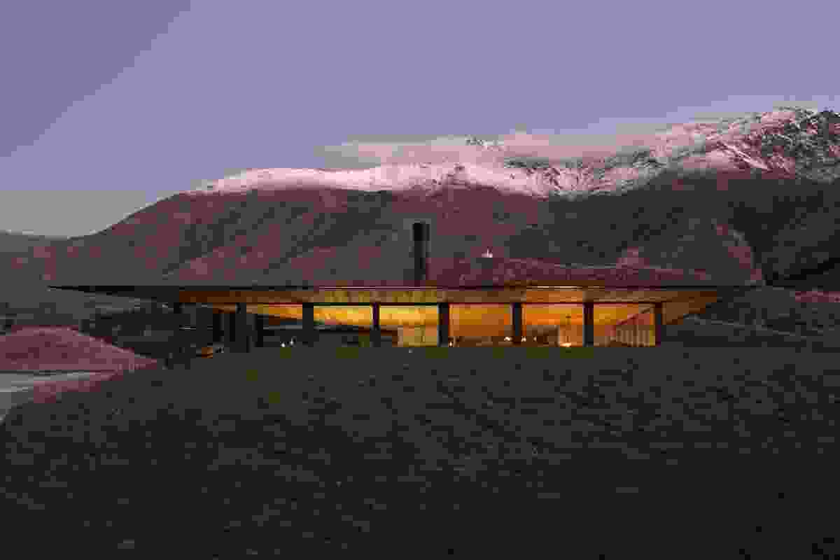 The home takes flight from the land against a backdrop of snow-capped mountains and rolling, grassy hills. 