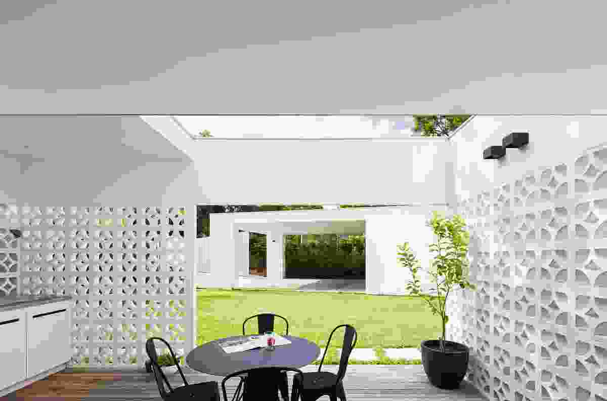 Breezeblock walls create outdoor rooms for various uses, a deck beyond the kitchen serving as an outdoor dining space.