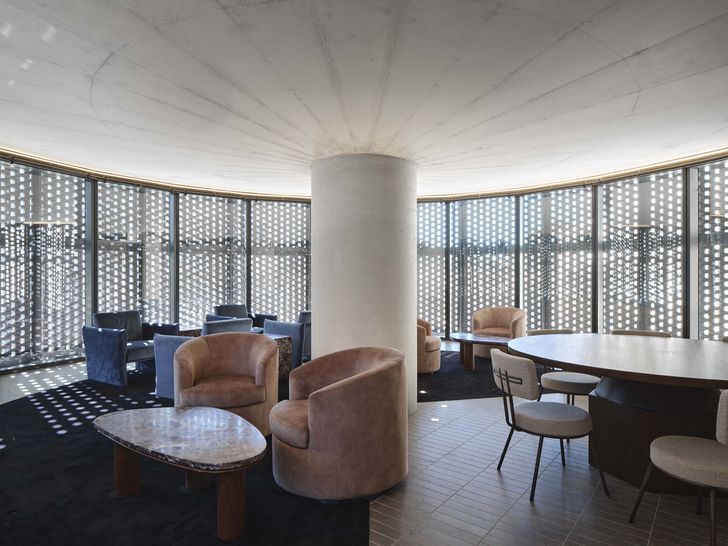 Additional retail functions are accommodated in two drum-shaped pavilions – each with a central concrete column that sprouts out to form a raking concrete soffit, from which a black hit-and-miss brickwork facade is hung.