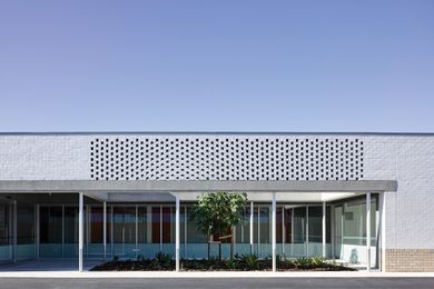 Hit-and-miss brickwork crowns the public entry, which faces the site’s northern boundary and carpark rather than the street.