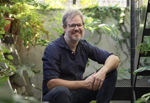 John Ellway sits on the stair of Terrarium House (2017), which occupies the former verandah of a compact cottage in Highgate Hill, Brisbane.