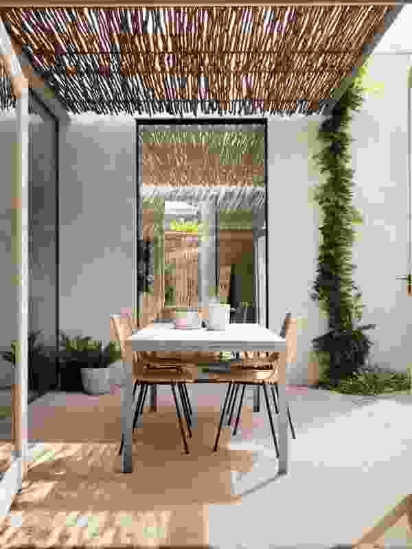 A pergola of reclaimed tea-tree sticks filters sunlight to create a play of shadows.

