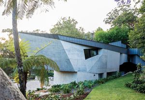 On arrival, visitors encounter a crescent-shaped house with a skin of angular concrete.