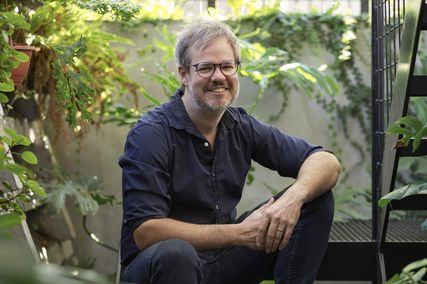 John Ellway sits on the stair of Terrarium House (2017), which occupies the former verandah of a compact cottage in Highgate Hill, Brisbane.