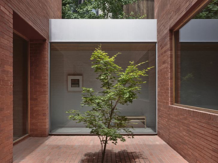 The white facade gives way to rendered red bricks beyond the entry. Artwork: Bruno Leti.