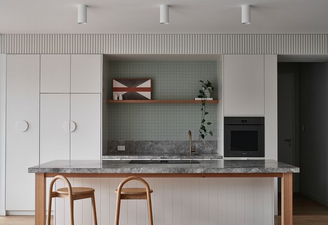 Rectangular limestone benchtops, circular handles and square tiles express the home’s playful geometric design. Artwork: Kasper Raglus; ceramics: David Shrigley.