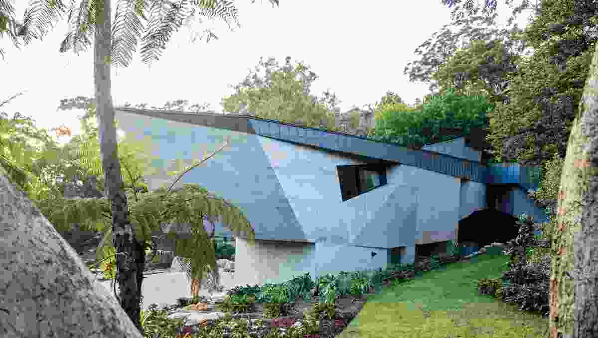 On arrival, visitors encounter a crescent-shaped house with a skin of angular concrete.