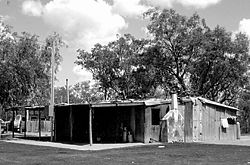 House 26. Built by one of Goodooga’s main ethno-architects, Clem Orcher, the house is constructed in two halves – one half can be lived in while the other is remodelled. (It has been rebuilt and redesigned about ten times.) A wide verandah was occupied nearly as much as the interior.